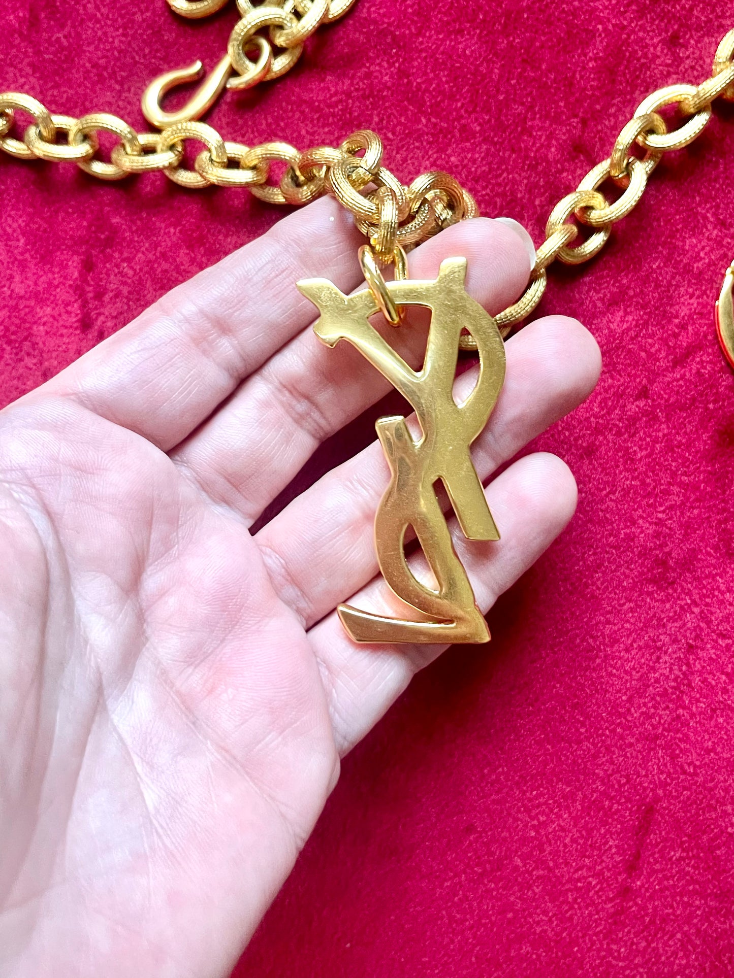 Backside view Displayed on hand Authentic YSL oversized gold logo bag charm pendant repurposed into a long chain necklace, close-up detail vintage Yves Saint Laurent 