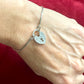 Silver Dior vintage bracelet with a heart-shaped padlock charm on a wrist against a red background