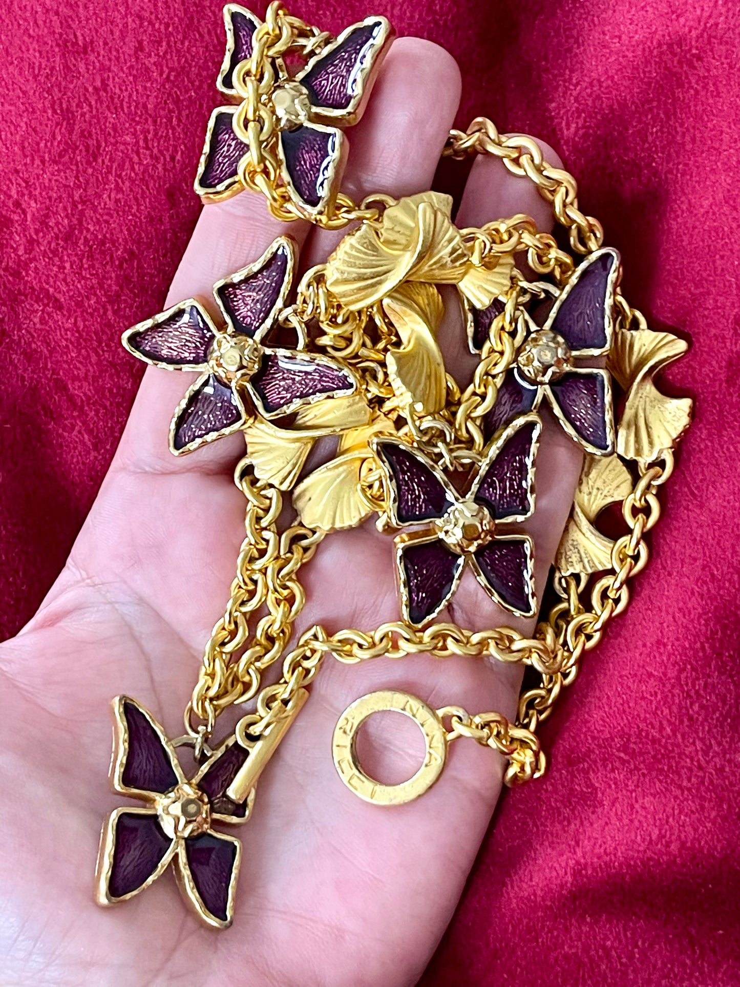 Vintage 80s five Yves Saint Laurent Butterfly Enameled pendants mounted on a Nina Ricci gold necklace, displayed on hand close up view 