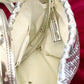 Inside view on removable straps inside the bag of Paco Rabanne silver shoulder/wrist bag with both straps shown, on red velvet fabric background.