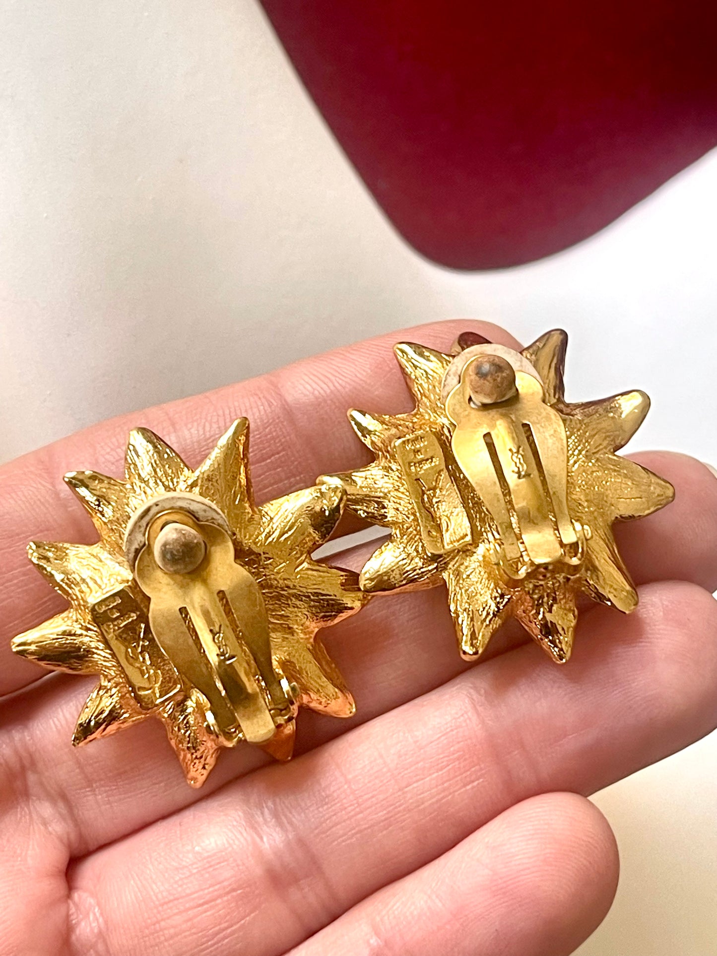 Showing a closeup on backside of Vintage Yves Saint Laurent gold-tone floral earrings with pearl center, signed YSL Made in France, 1980s designer jewelry displayed on hand