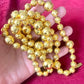Held by hand Close-up of YSL vintage gold bead necklace showing 18K refurbished shine and textured detailing vintage Yves Saint Laurent 