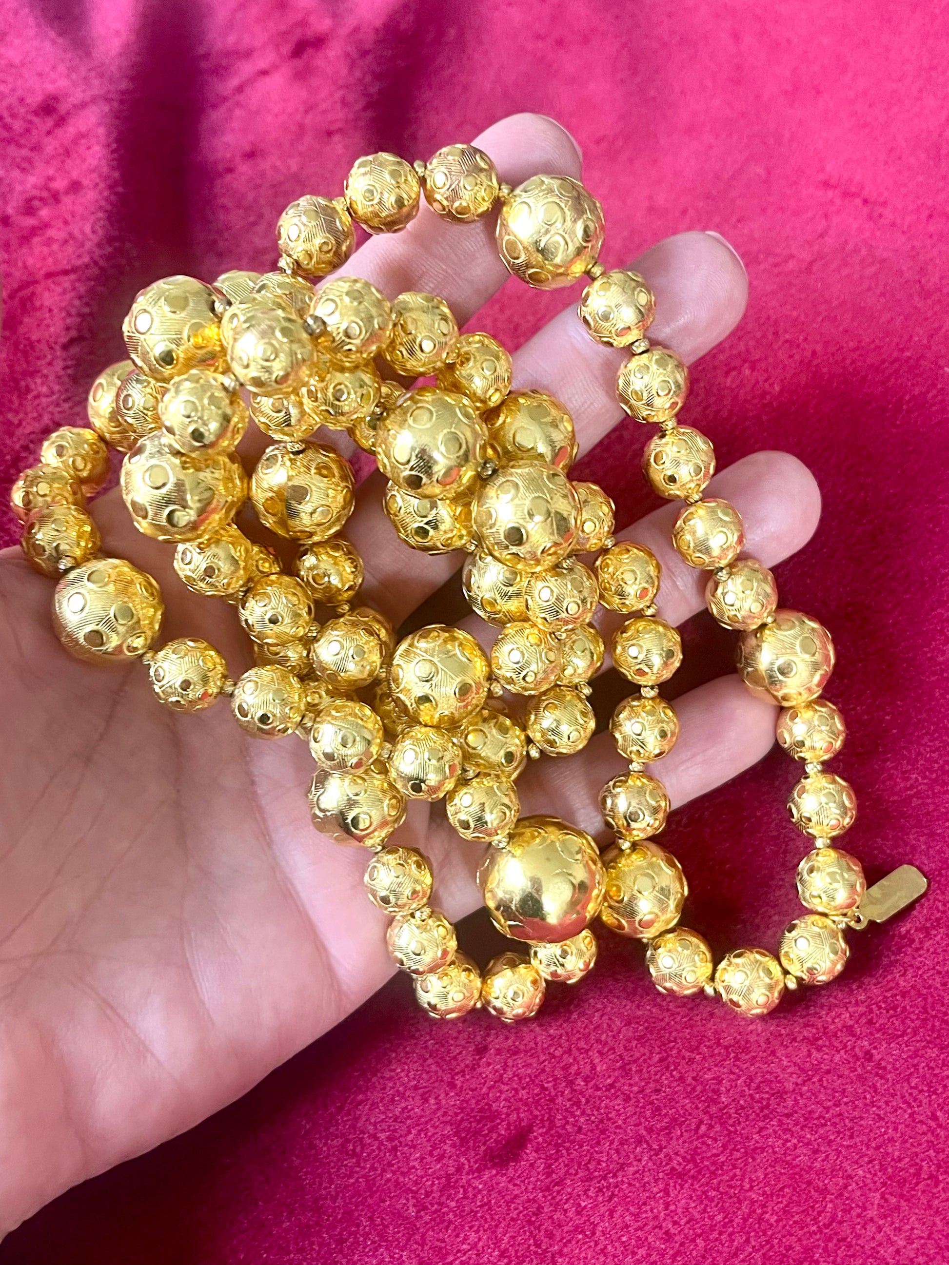 Held by hand Close-up of YSL vintage gold bead necklace showing 18K refurbished shine and textured detailing vintage Yves Saint Laurent 