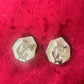 Silver vintage Yves Saint Laurent hexagonal earrings on a red textured background