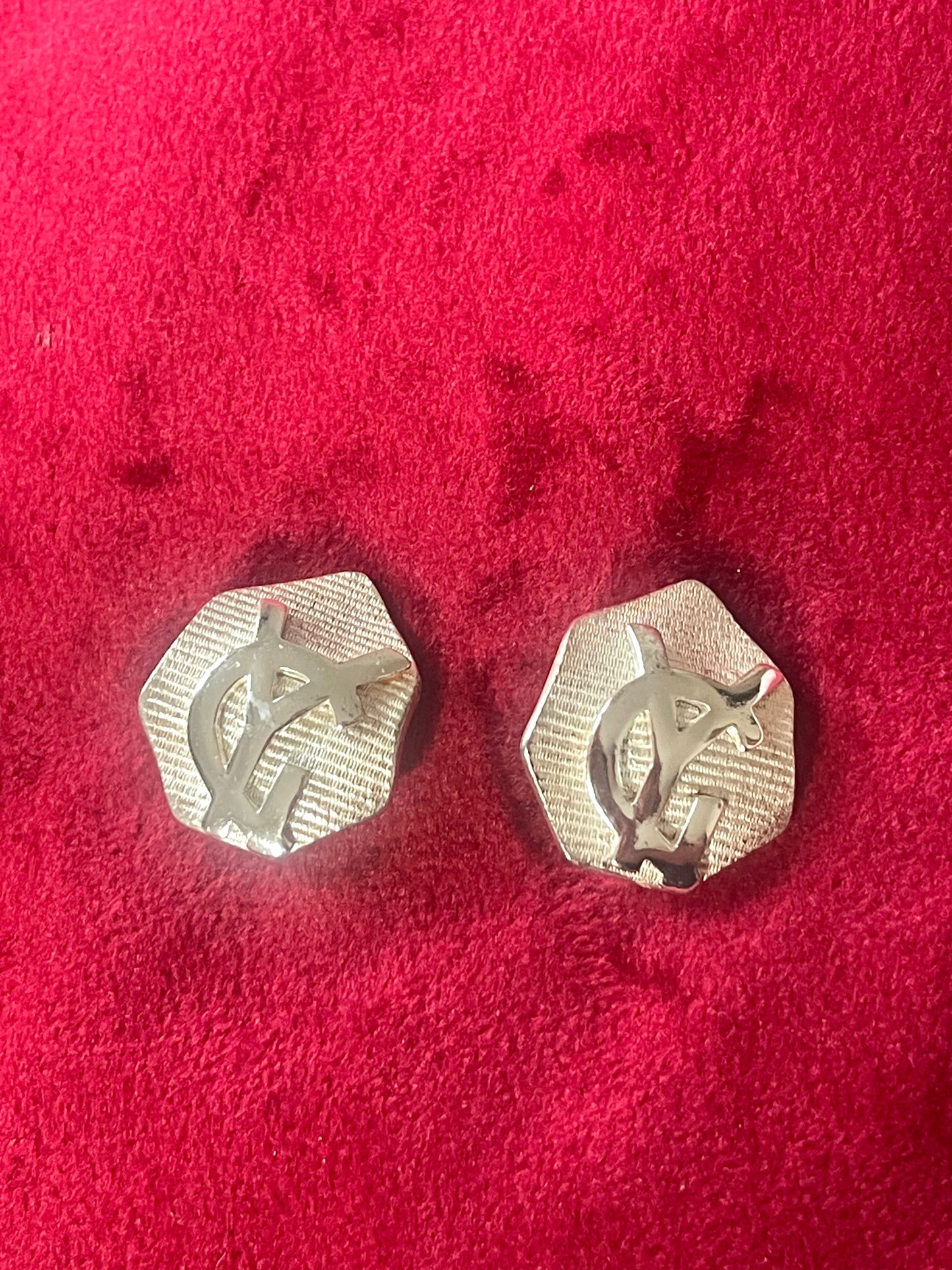 Silver vintage Yves Saint Laurent hexagonal earrings on a red textured background