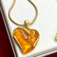 Close up on vintage YSL necklace with orange resin pendant on white background