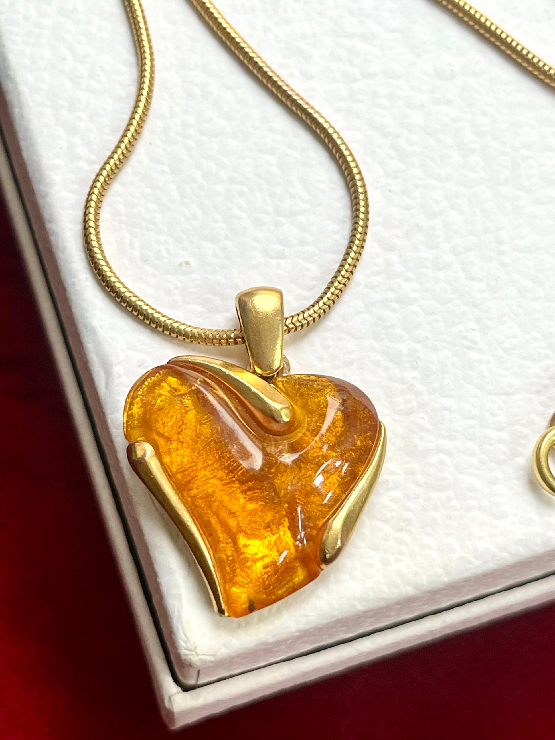 Close up on vintage YSL necklace with orange resin pendant on white background