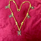 Vintage 80s five Yves Saint Laurent Butterfly Enameled pendants mounted on a Nina Ricci gold necklace, displayed on a red velvet background 