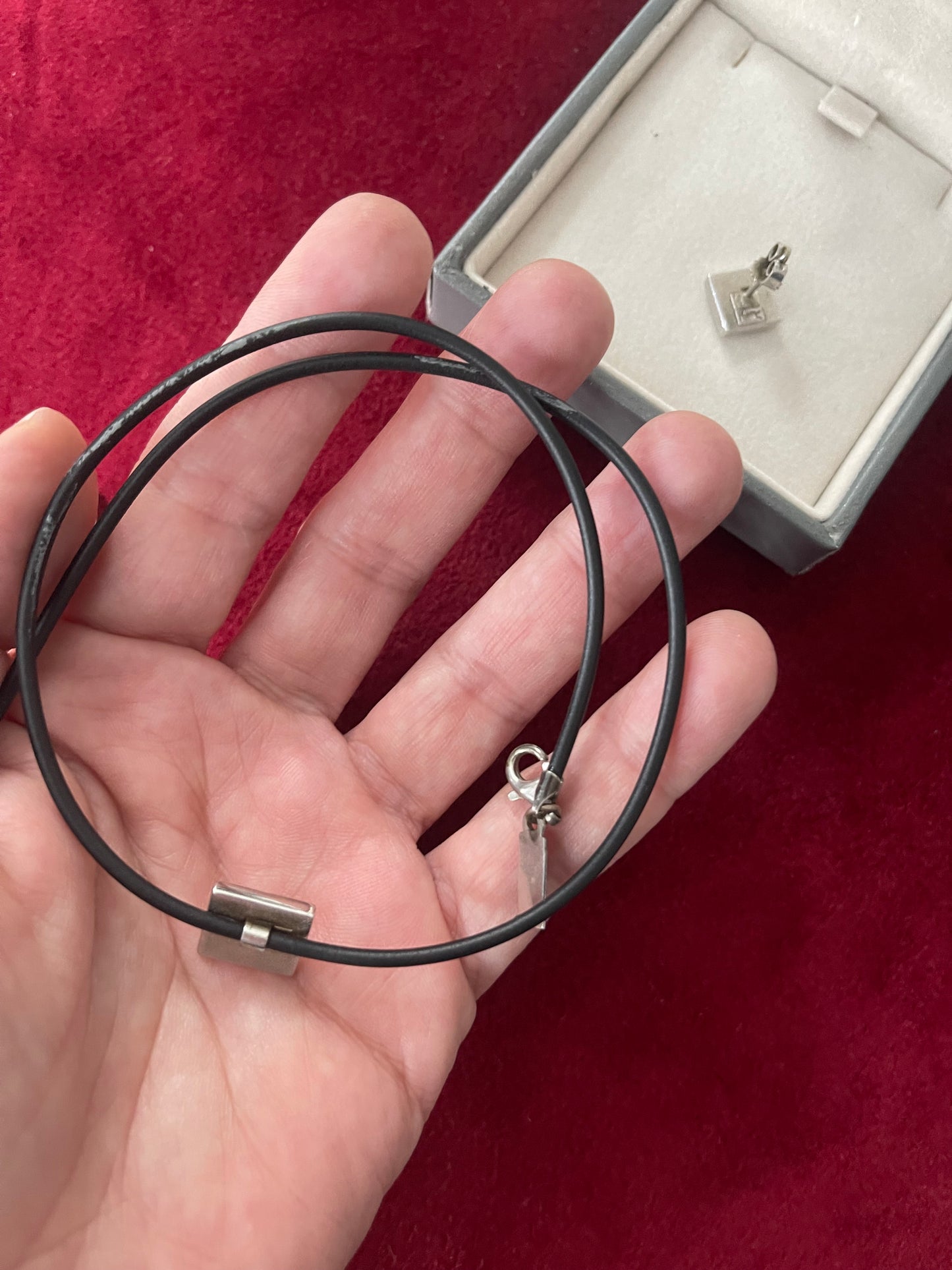 Close-up of black necklace cord showing light signs of wear on YSL silver pendant set, displayed On hand 