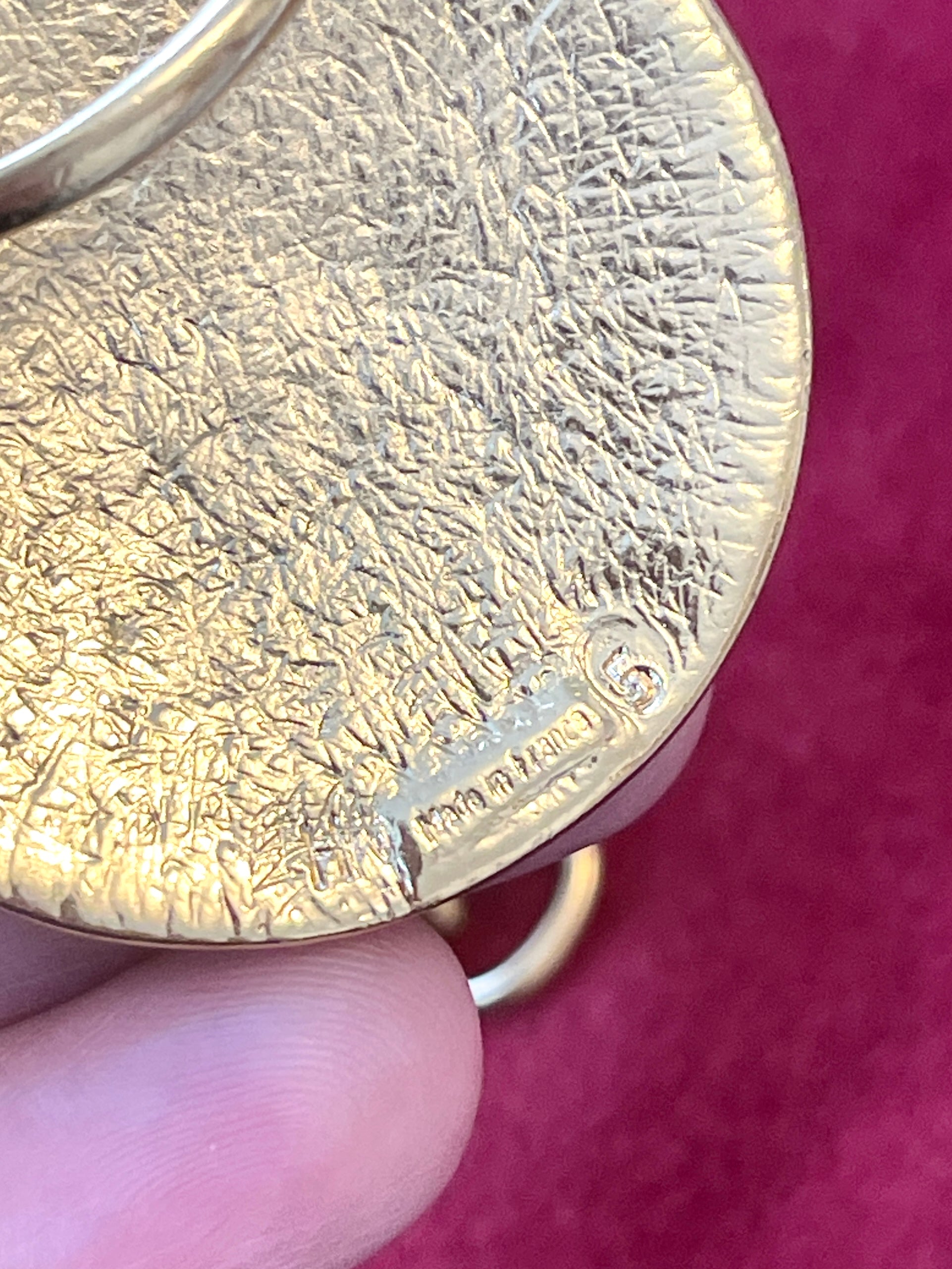 Gold vintage Yves Saint Laurent with engraved made in France held by a hand against a red background