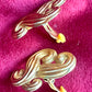Close-up of side view vintage Nina Ricci swirly heart earrings with sculptural design in matte gold tone