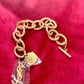 Detail view of YSL monogram charm hanging from gold vintage Yves Saint Laurent bracelet.