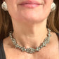 Close-up of a model wearing a vintage Yves Saint Laurent silver necklace with hexagonal YSL Monogram earrings.