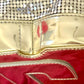 Close up on signs of wear of Paco Rabanne silver shoulder/wrist bag with both straps shown, on red velvet fabric background.