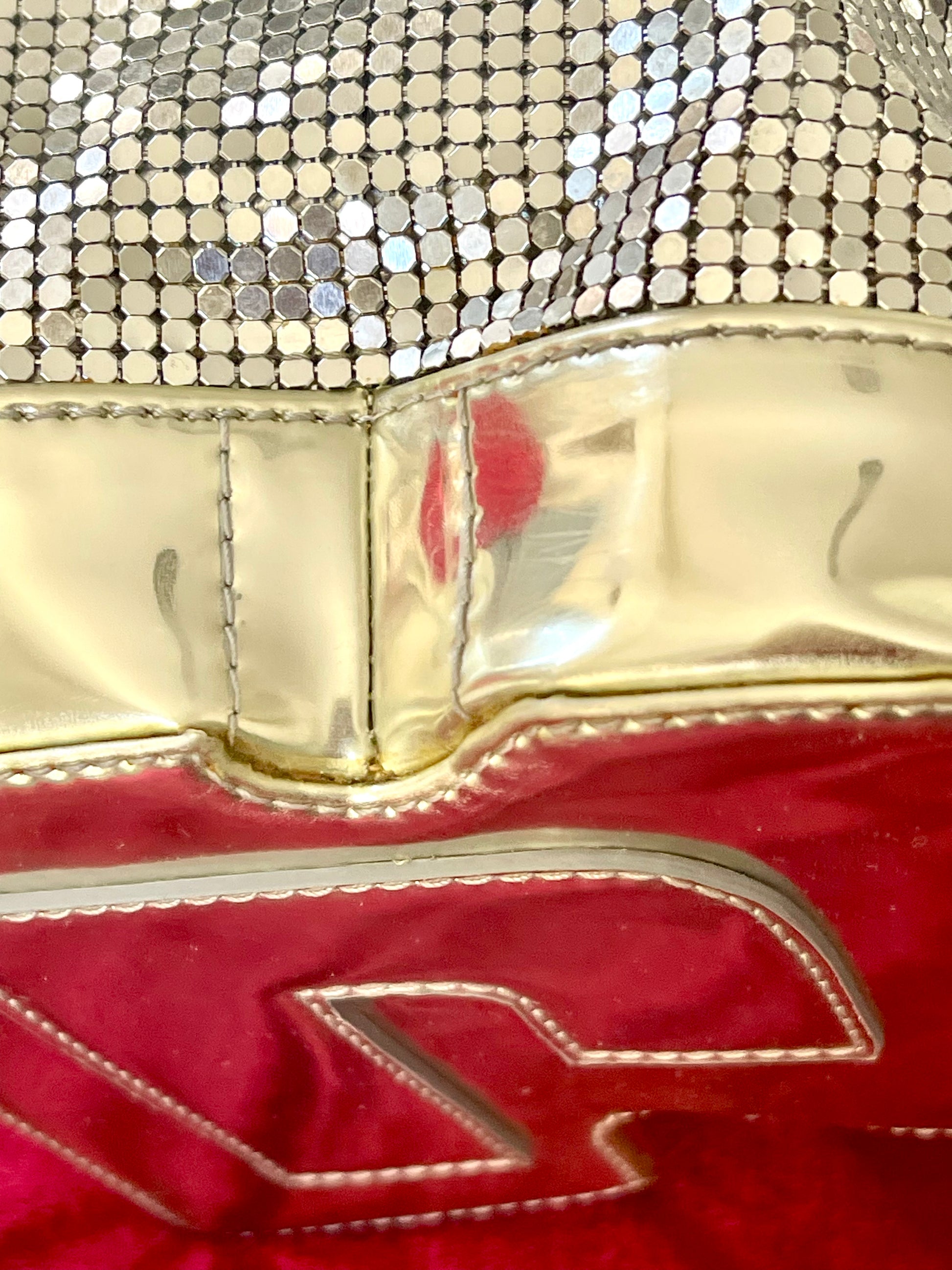 Close up on signs of wear of Paco Rabanne silver shoulder/wrist bag with both straps shown, on red velvet fabric background.
