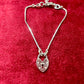 Dior silver tone bracelet with a heart -shaped lock pendant on a red textured background