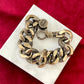 Top view Preloved YSL bronze and grey chain worn as a statement piece against white background with red velvet 