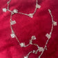 Two connected upcycled Dior Beauté phone charm necklace with removable silver-tone charms on a red background 