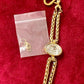 YSL gold tone statement bracelet with oval crystal centerpiece And removed hoops for smaller size on a red background 