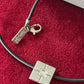 Detailed view of vintage YSL silver 925 pendant on a black cord photographed on red velvet.