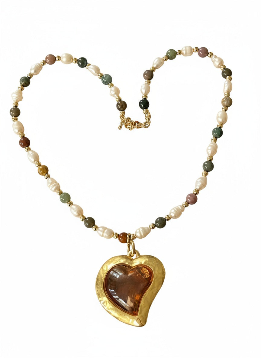 Pearl Necklace with vintage Yves Saint Laurent heart-shaped flower petal pendant on white background 