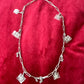 Upcycled Dior Beauté phone charm necklace with removable silver-tone charms On a red background 
