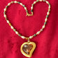 Pearl Necklace with vintage Yves Saint Laurent heart-shaped flower petal pendant on a red background