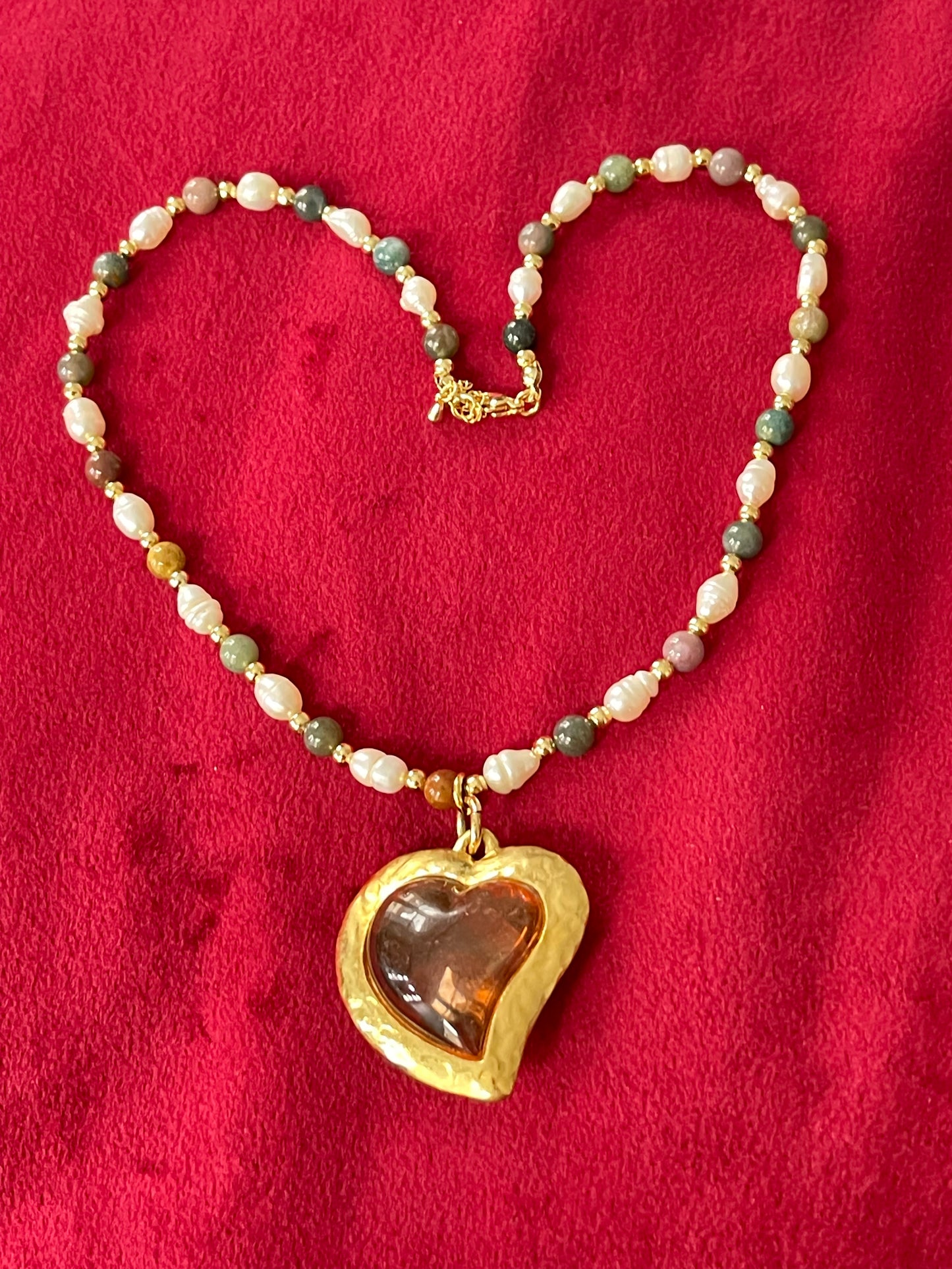Pearl Necklace with vintage Yves Saint Laurent heart-shaped flower petal pendant on a red background