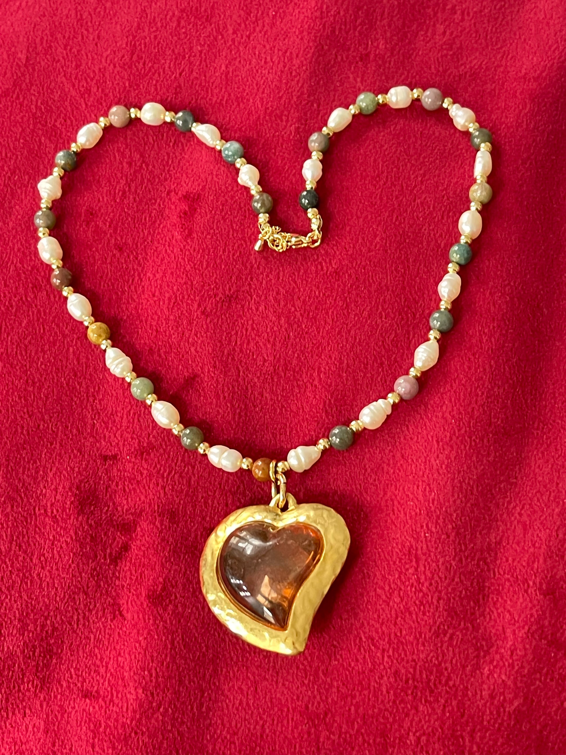 Pearl Necklace with vintage Yves Saint Laurent heart-shaped flower petal pendant on a red background