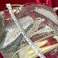 Length view of Paco Rabanne silver shoulder/wrist bag with both straps shown, on red velvet fabric background with measuring tape 