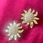 Vintage Yves Saint Laurent Gold sun-shaped earrings with rhinestones on a pink background
