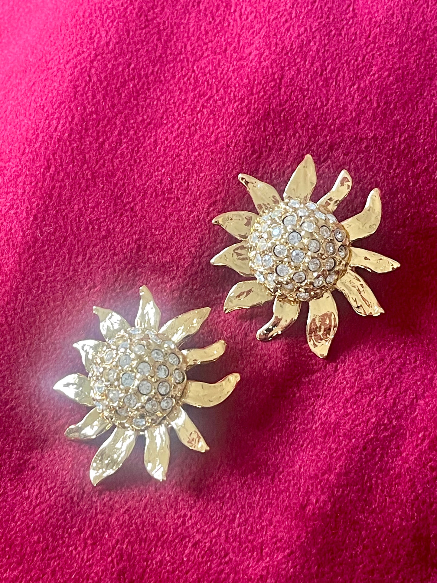 Vintage Yves Saint Laurent Gold sun-shaped earrings with rhinestones on a pink background