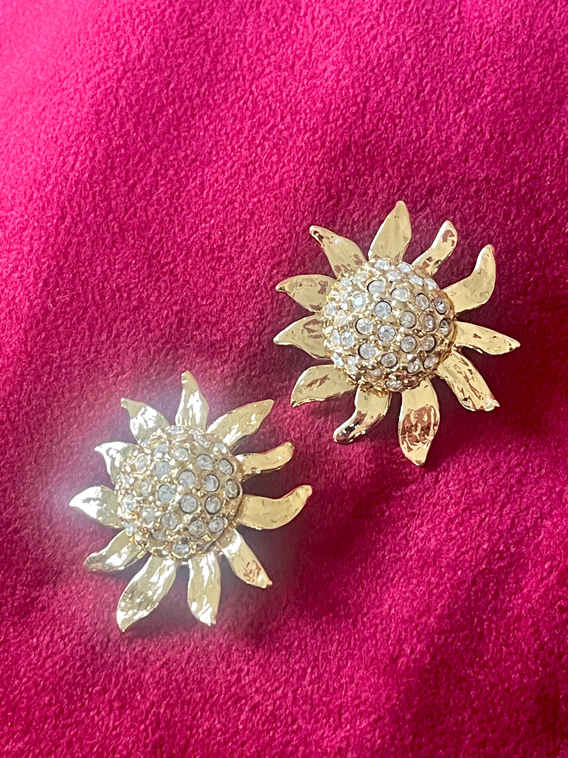 Vintage Yves Saint Laurent Gold sun-shaped earrings with rhinestones on a pink background