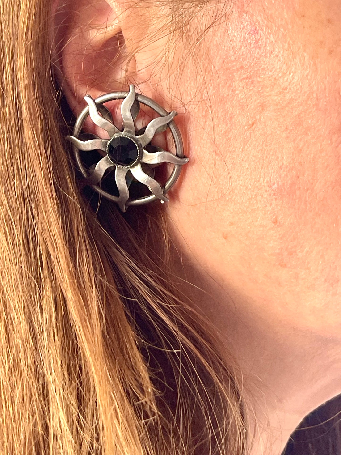 Model wearing 1980s Paco Rabanne silver-tone sun earrings with dark faceted center stones, highlighting detailing and condition.