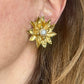 Yves Saint Laurent Gold flower-shaped earring with a pearl center worn by a person.