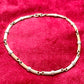 Vintage Christian Dior two-tone necklace with ribbed accents displayed on a red velvet background