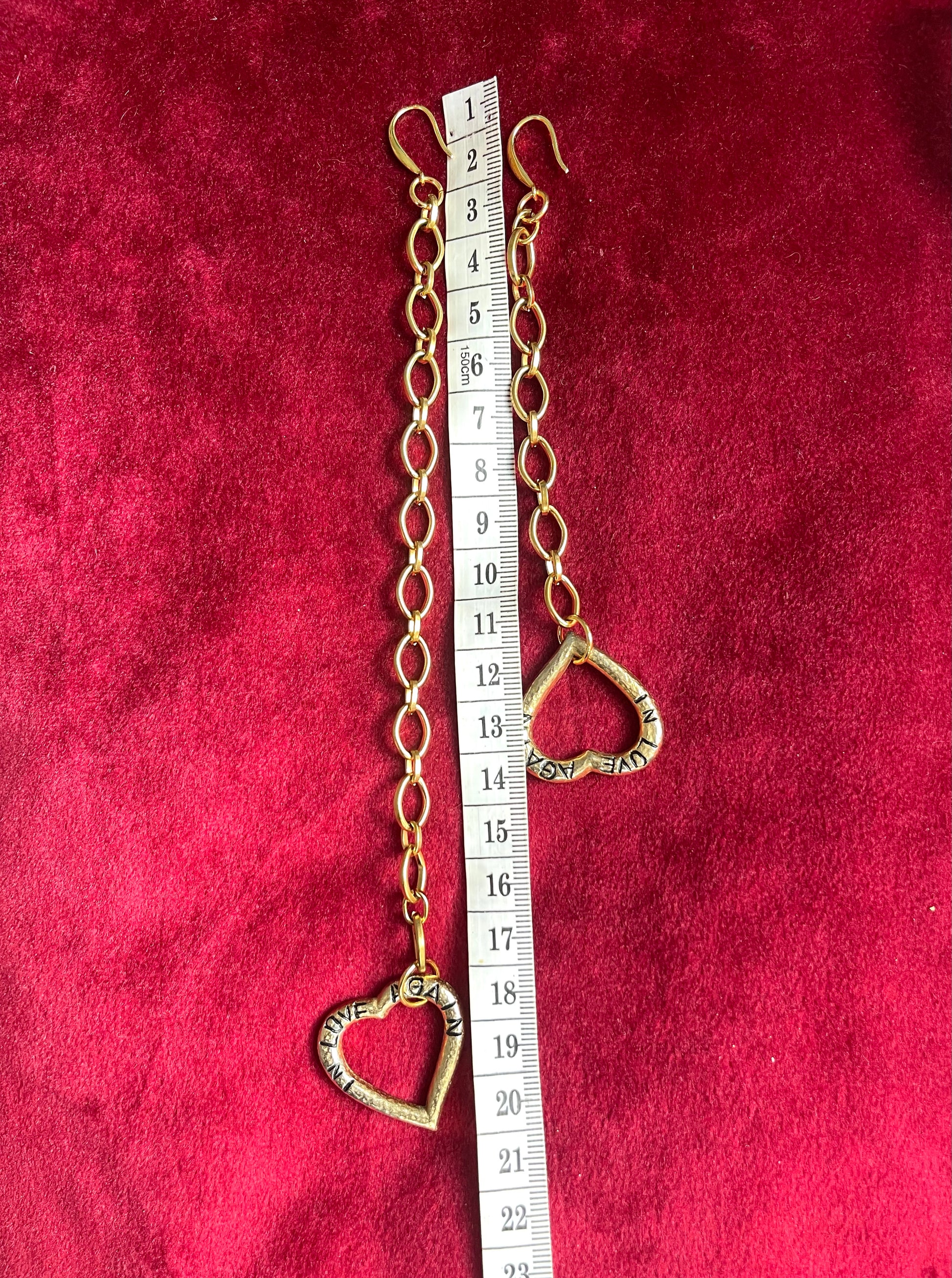 YSL earrings on hand, red background contrast Using a measuring tape 