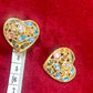 Pair of 3 cm gold-tone vintage Yves Saint Laurent heart-shaped clip-on earrings decorated with multi-coloured crystals, displayed on a red background Using a Measuring Tape 