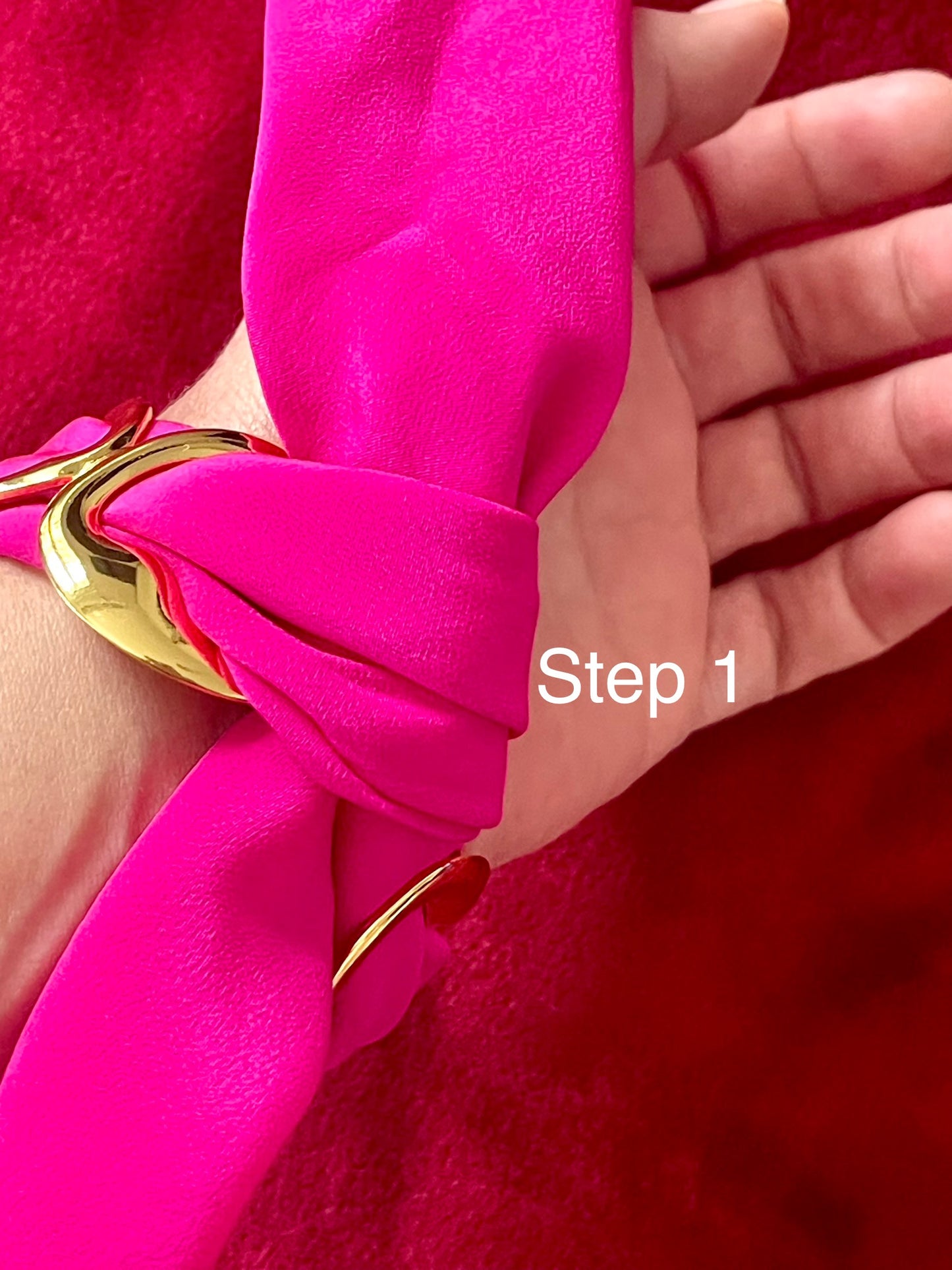 Close-up of a hand wearing a bright  Dior pink scarf bracelet set  with a gold accent , labeled 'Step 1'.