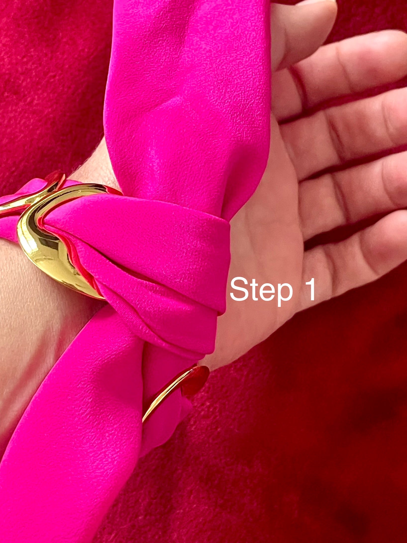 Close-up of a hand wearing a bright  Dior pink scarf bracelet set  with a gold accent , labeled 'Step 1'.