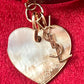 Heart-shaped seashell pendant with 'Yves Saint Laurent' logo on a red background