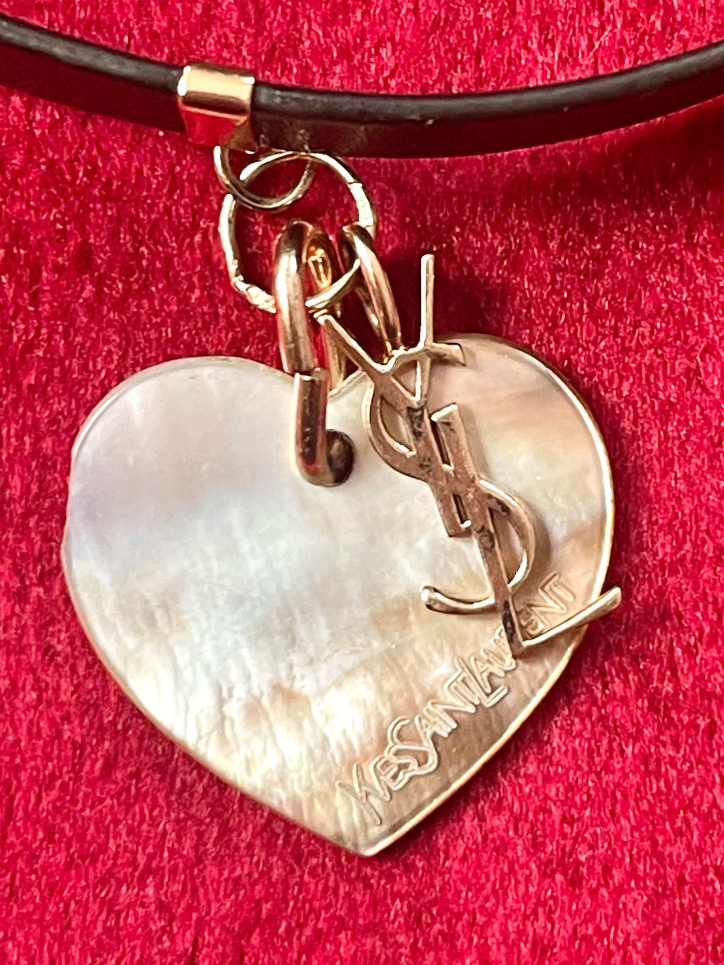 Heart-shaped seashell pendant with 'Yves Saint Laurent' logo on a red background