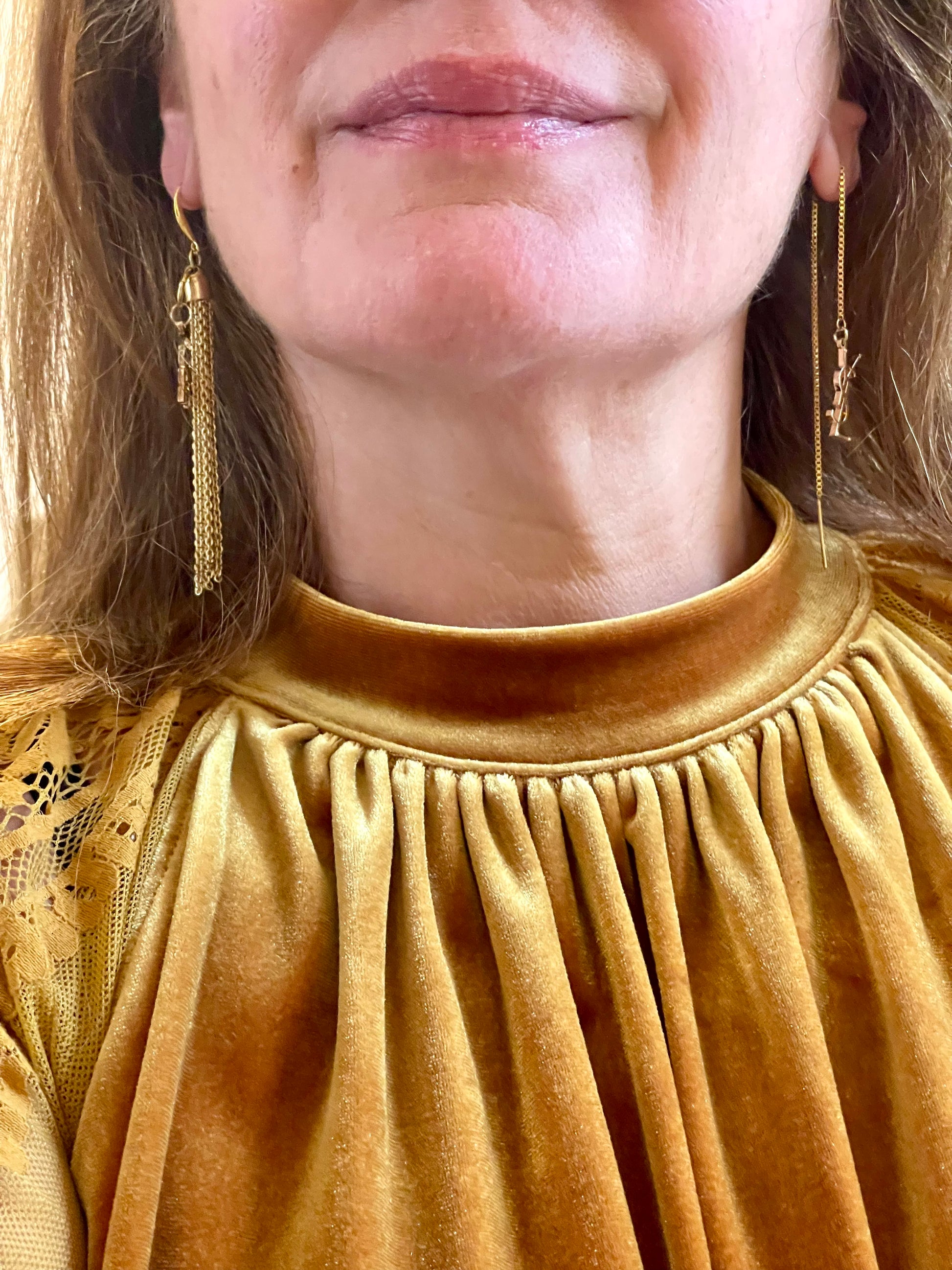 Close up of a model wearing a pair of earrings, gold tassel repurposed Yves Saint Laurent Libre charms 