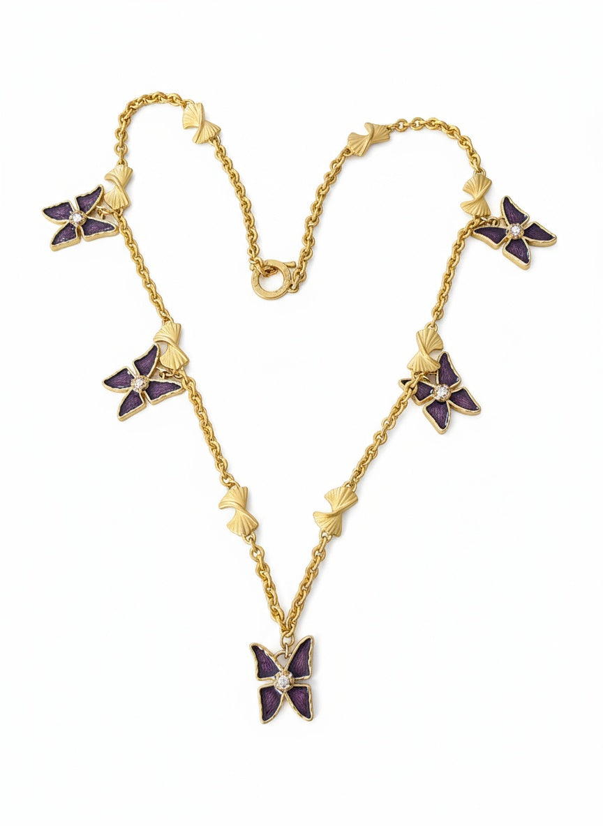 Vintage Nina Ricci necklace with five attached Yves Saint Laurent pendants displayed on red velvet background.
