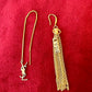Gold YSL earring with chain and tassel on a red background