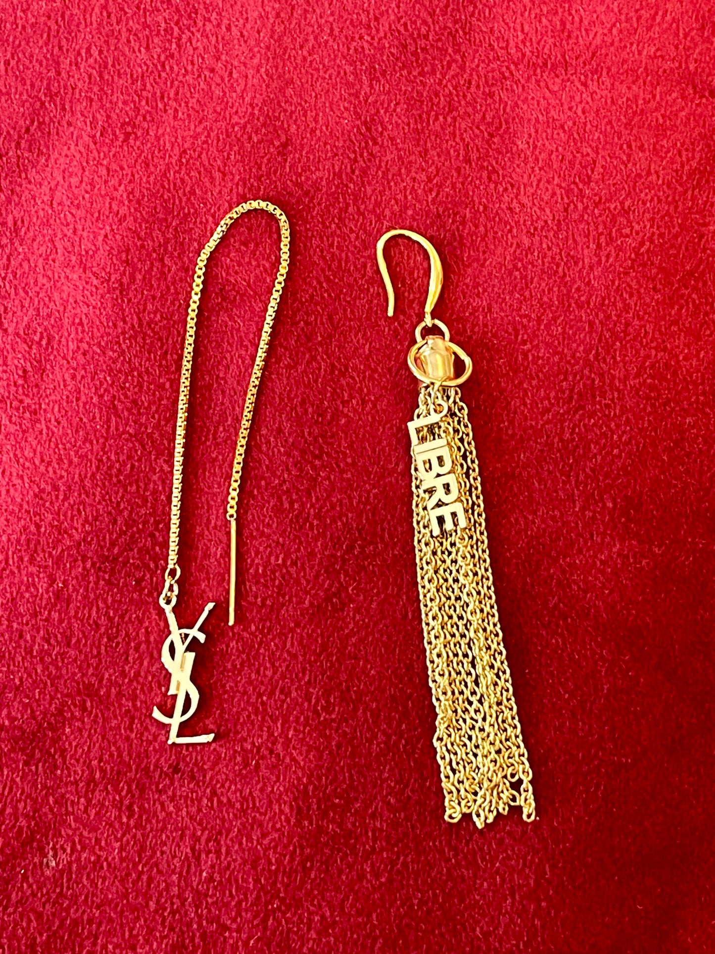 Gold YSL earring with chain and tassel on a red background