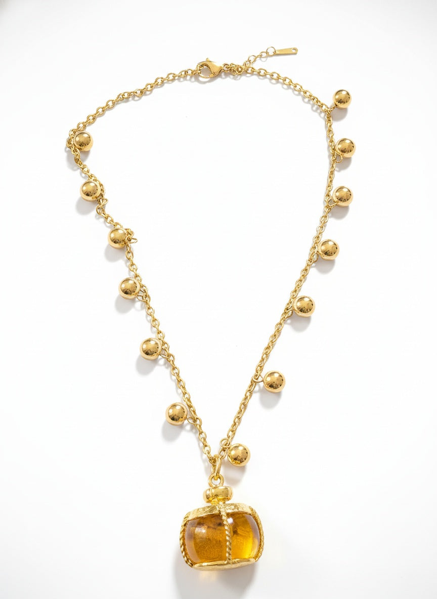 Gold necklace with a yellow pendant on a white background