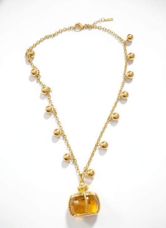 Gold necklace with a yellow pendant on a white background