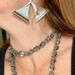 Close-up of a person wearing vintage Paco Rabanne geometric silver earrings and a chain necklace.