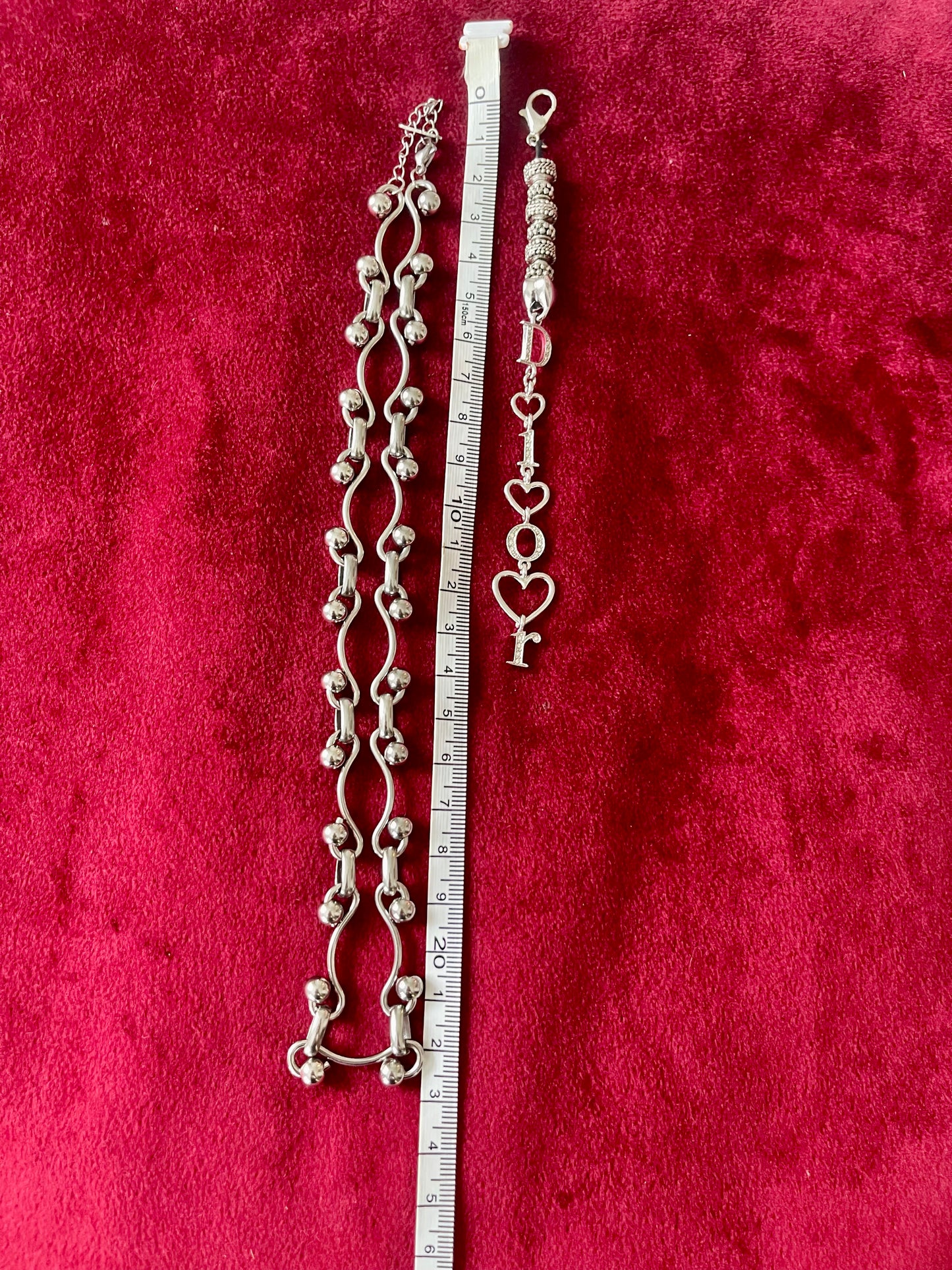  Dior phone charm pendant with silver beads and clasp detail, highlighting one-of-a-kind design using measuring tape on red background .